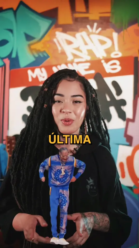 Lírios segura um boneco do Snoop Dogg diante de um muro de graffiti